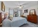 Cozy bedroom featuring a bed, windows with curtains, ceiling fan and a wooden dresser with mirror at 111 Lynnette Dr, Mt Ulla, NC 28125