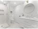 Bright bathroom boasts marble flooring, a frameless glass shower, and a vanity with a circular mirror at 16439 Jetton Rd, Cornelius, NC 28031