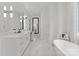 Bright bathroom featuring marble floors, white cabinets, a soaking tub, and modern gold fixtures at 16439 Jetton Rd, Cornelius, NC 28031