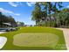A beautiful backyard putting green stretches towards the lake, complete with lounge chairs and lush trees at 16439 Jetton Rd, Cornelius, NC 28031