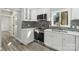 Modern kitchen with white cabinets, stainless steel appliances, gray backsplash, and updated flooring at 5717 Ruth Dr, Charlotte, NC 28215