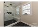 Modern bathroom with glass shower, black tile accents, and window view at 603 N Elm St, Cherryville, NC 28021