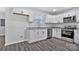 Modern kitchen with white cabinets, granite countertops, stainless steel appliances and gray wood-look flooring at 606 N Elm St, Marshville, NC 28103