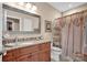 Well-lit bathroom featuring a granite countertop, wood cabinets, large mirror, and a matching wood framed art piece at 8439 Sonata Ct, Denver, NC 28037