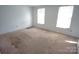 Spacious bedroom with a worn carpet, two windows and base electrical outlets at 8915 Touchstone Ln, Charlotte, NC 28227