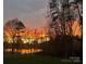 Backyard view of sunset over trees and lake, with a small fence at 110 Hazelton Loop, Mooresville, NC 28117