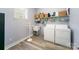 Bright laundry room with washer, dryer, shelving, utility sink, and wood-look floors at 110 Hazelton Loop, Mooresville, NC 28117