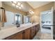 Bright bathroom with double sink vanity, modern lighting, and entry to bedroom with large bed at 1122 Saratoga Blvd, Indian Trail, NC 28079