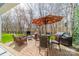 Paver patio with outdoor seating, table, grill, umbrella, and wooded backdrop at 1122 Saratoga Blvd, Indian Trail, NC 28079
