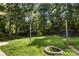 Lush backyard with mature trees, a fire pit, dog kennel, and charming string lights; creating a relaxing outdoor oasis at 1210 Brookwood Dr, Shelby, NC 28150