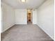 A carpeted bedroom showcasing a window, hallway access and a view of the en suite bathroom at 12616 Tucker Crossing Ln, Charlotte, NC 28273