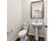 This powder room features a pedestal sink, decorative mirror, and wood-look flooring at 14030 Turncloak Dr, Charlotte, NC 28278