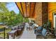 Long, covered outdoor patio featuring stone accents, tiled floor, and plenty of seating overlooking the property's landscape at 16 Sunrise Point Ct, Lake Wylie, SC 29710