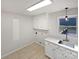Bright laundry room featuring tile floors, upper and lower cabinets, and a stainless steel sink at 189 Beech Brook Ln, Statesville, NC 28625