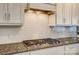 Granite countertops and gas cooktop with stainless steel vent hood in a modern kitchen at 2056 Angel Oak Dr, Fort Mill, SC 29715