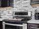 Close-up showcasing a modern stainless steel range with gray backsplash and dark cabinetry at 2100 Bluebonnet Ln, Matthews, NC 28104