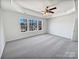 This is a bright, carpeted primary bedroom with a ceiling fan and multiple windows at 21005 Brinkley St, Cornelius, NC 28031