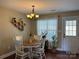Bright dining area featuring a wooden table with white chairs, decorative lighting, and a large window at 321 Creek Se Trl, Concord, NC 28025