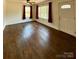 Living room featuring dark hardwood floors, two windows, door, and burgundy curtains at 3437 Wilkesboro Hwy, Statesville, NC 28625