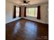 Living room showcasing hardwood floors, ceiling fan, windows, and burgundy curtains at 3437 Wilkesboro Hwy, Statesville, NC 28625