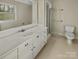 Bright bathroom features a large mirror, white vanity, a toilet and a glass enclosed shower at 6813 Linda Lake Dr, Charlotte, NC 28215