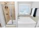 Bright bathroom featuring a shower with glass enclosure and a soaking tub with a large window at 815 Oak Embers Se Dr, Concord, NC 28025