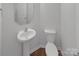 Bathroom featuring a pedestal sink, toilet and neutral decor on a wood look floor, providing a fresh, clean look at 9154 Bradstreet Commons Way, Charlotte, NC 28215