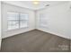 Bright bedroom with neutral carpet, white walls, two windows with blinds, and ceiling light fixture at 9407 Seamill Rd, Charlotte, NC 28278