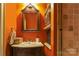 Bathroom features a vintage vanity with sink, wall shelving, and decorative mirror at 1001 Parkwood Ave, Charlotte, NC 28205