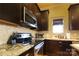Close-up of kitchen area with stainless steel range, microwave, granite counters, and dark wood cabinets at 1001 Parkwood Ave, Charlotte, NC 28205