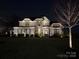 Eye-catching two-story brick home with exterior lighting, highlighting its architectural details and curb appeal at night at 1005 Cherry Laurel Dr, Waxhaw, NC 28173