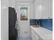 Bright laundry room with stackable washer/dryer, blue tiled backsplash, and ample white cabinet space at 13500 Robert Walker Dr, Davidson, NC 28036