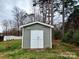 Close up of a small gray shed with white doors, surrounded by a grassy yard and trees at 1532 South Point Rd, Belmont, NC 28012