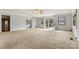 Expansive living room with neutral carpet, ample natural light from windows and glass doors, and a ceiling fan for added comfort at 156 Hazelton Loop, Mooresville, NC 28117