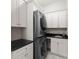 Well-lit laundry room with white cabinets, black countertops, sink, and modern, front-loading, stackable washer and dryer at 21013 Island Forest Dr, Cornelius, NC 28031