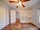 This bedroom features hardwood floors, a ceiling fan, bright white built in shelving, and a window allowing for natural light at 211 9Th St, Belmont, NC 28012