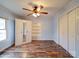 This bedroom features hardwood floors, a ceiling fan, bright white built in shelving, closet and natural light from the window at 211 9Th St, Belmont, NC 28012