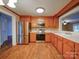 Well-lit kitchen boasting stainless steel appliances, wooden cabinets, and a view into the Gathering room at 211 9Th St, Belmont, NC 28012