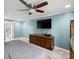 Bright main bedroom featuring a ceiling fan, mounted TV, and a doorway leading to the en suite bathroom at 2200 Peninsula Ave, Shelby, NC 28150