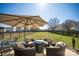 A backyard patio with outdoor seating under a large umbrella, and a view of the expansive lawn and fence at 4729 Abercromby St, Charlotte, NC 28213