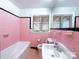 Bright bathroom featuring pink tiles, a sink, toilet, bathtub, and two windows at 4800 Kipling Dr, Charlotte, NC 28212