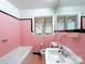 Bright bathroom featuring pink tiles, a sink, toilet, bathtub, and two windows at 4800 Kipling Dr, Charlotte, NC 28212