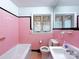 Bright bathroom featuring pink tiles, a sink, toilet, bathtub, and two windows at 4800 Kipling Dr, Charlotte, NC 28212