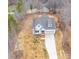 Aerial view of a charming white home with a gray roof, front-facing garage, and long driveway on a wooded lot at 5101 Thornhill Dr, Gastonia, NC 28052