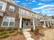 Attractive townhome featuring brick and siding, a covered front porch, and professionally landscaped yard under a blue sky at 5220 Kinsbridge Dr, Charlotte, NC 28227