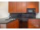 The kitchen has wood cabinetry, black countertops, a modern backsplash, and updated appliances at 525 E Sixth St # 208, Charlotte, NC 28202
