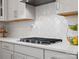 Modern kitchen featuring a stainless cooktop, stylish backsplash, and quartz countertops at 5585 Zeeland Ln, Fort Mill, SC 29707