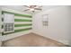 Bedroom featuring vibrant green striped accent wall, neutral carpet, and a ceiling fan at 6027 Edinmeadow Ln # 29, Charlotte, NC 28269