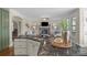 Kitchen island with sink and view of the living room with a fireplace and large windows at 805 Hidden Pond Ln, Waxhaw, NC 28173