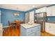 Bright kitchen features blue walls, an island with grey counters, stainless steel fridge, and a dining table at 919 42Nd Avenue Ne Ln, Hickory, NC 28601